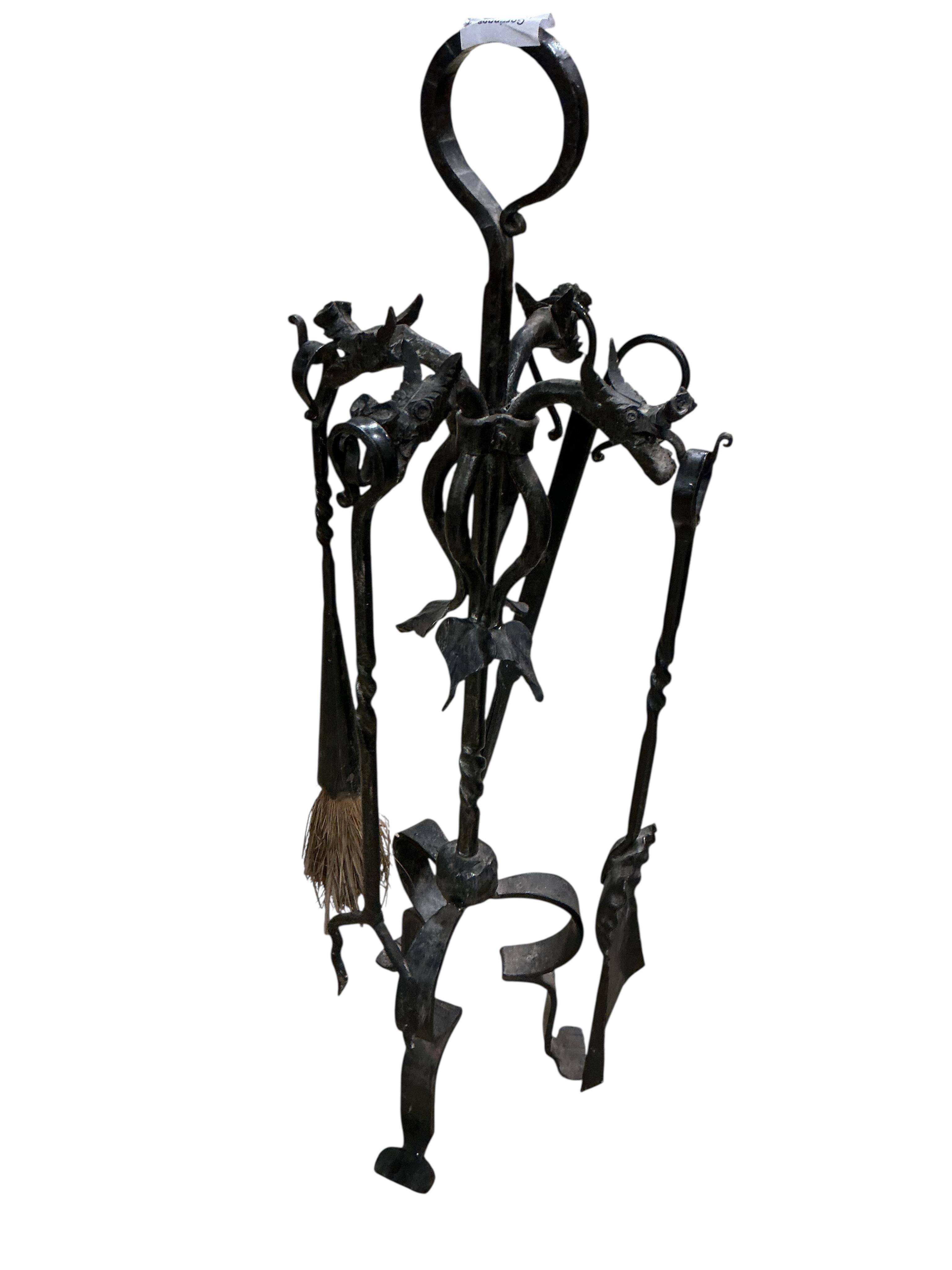 A set of wrought iron fire implements on dragon head stand